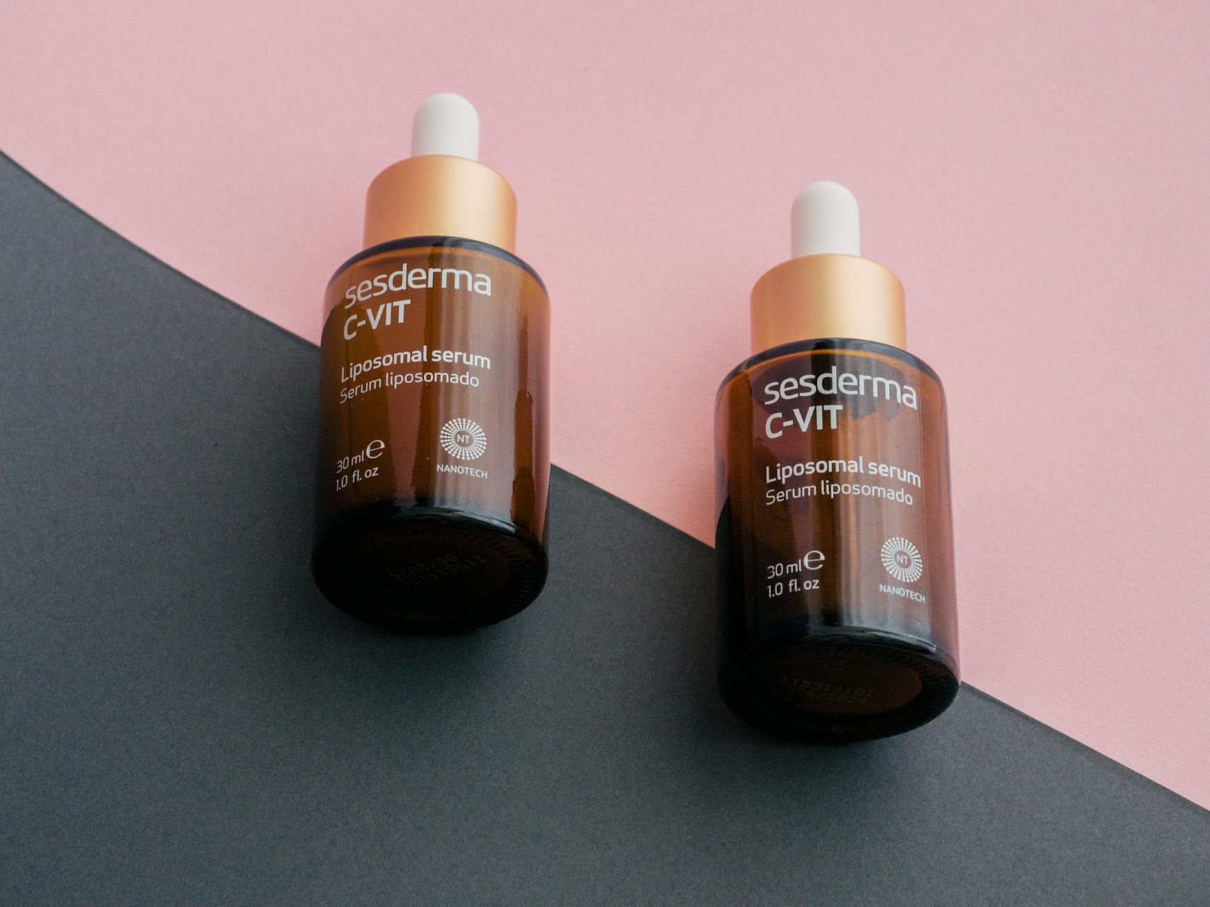 Dwie butelki serum Sesderma C-Vit z pipetą na różowo-szarym tle