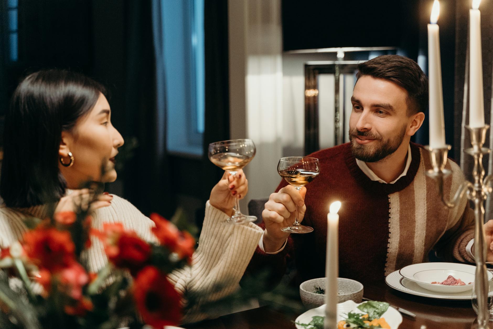 Para przy świecach pije wino przy romantycznej kolacji w domu