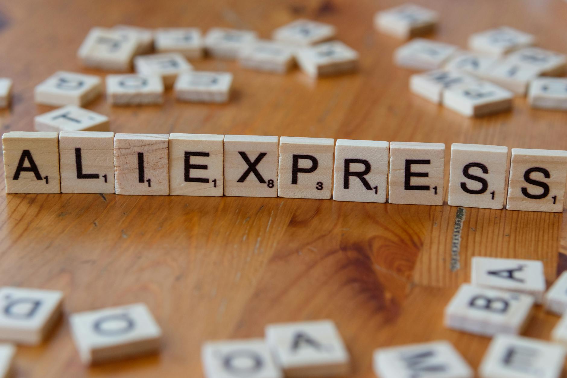 Klocki Scrabble układające napis AliExpress na drewnianym blacie