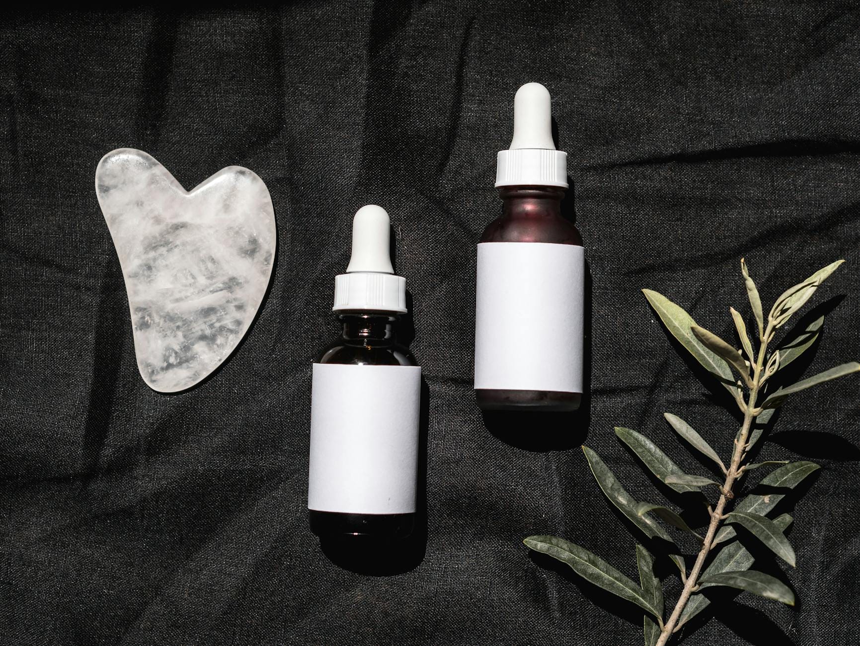 Minimalistyczny zestaw kosmetyków z gua sha na ciemnym tle
