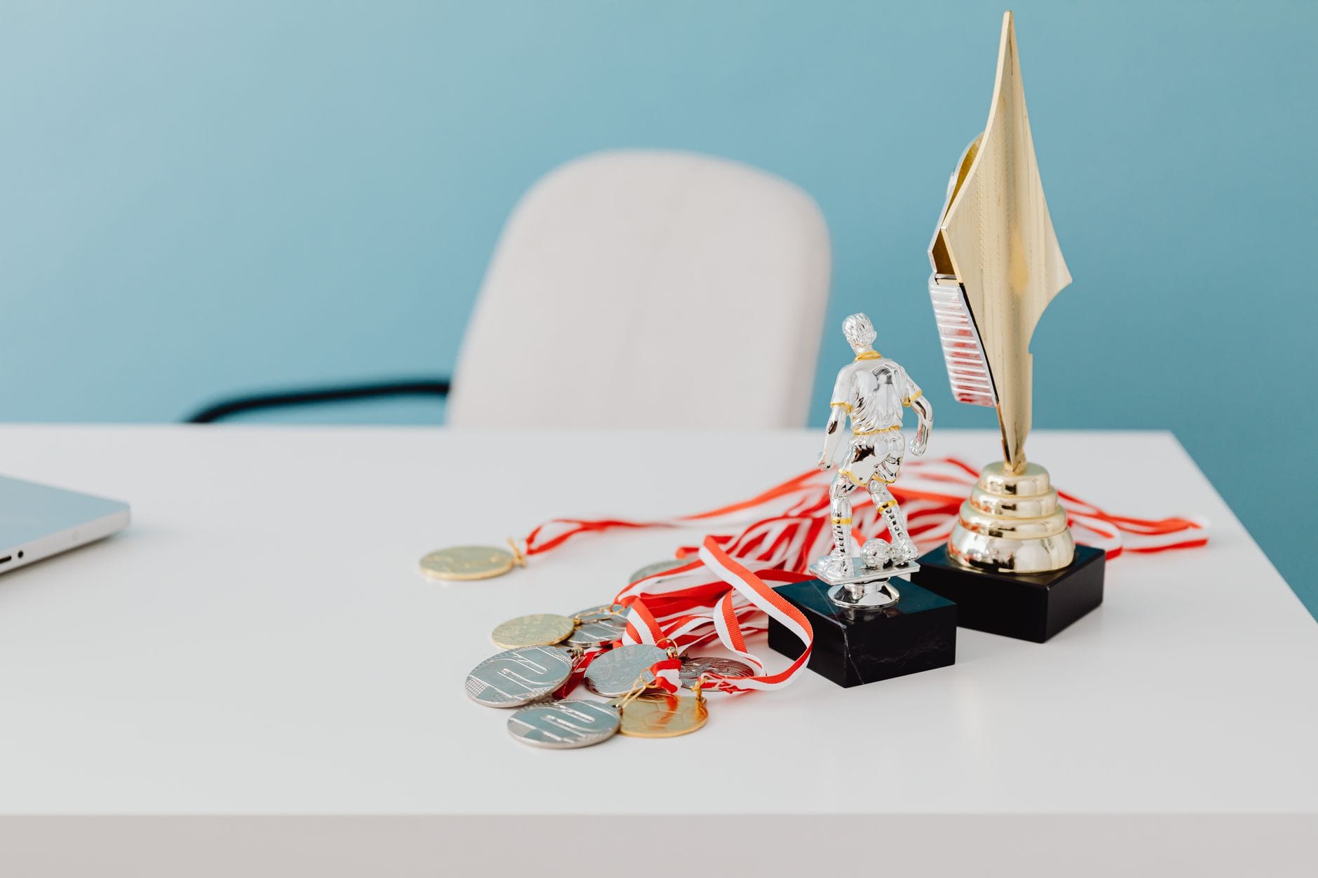 Personalizowane medale i puchary sportowe – jak zaprojektować nagrody, które naprawdę motywują Medale i puchary sportowe ustawione na białym biurku